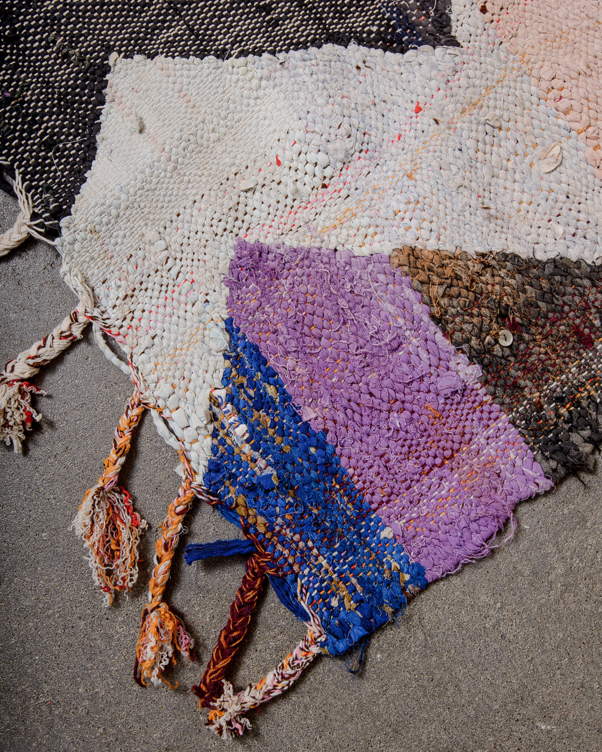 Corner of vintage kelim rug with cotton tassels in different colour combinations.